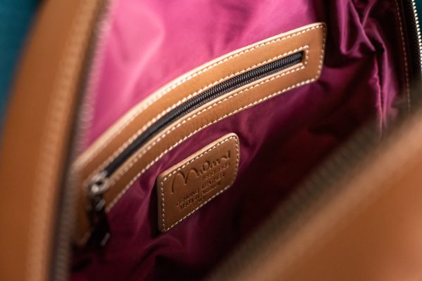 zaino in pelle color cuoio, dettaglio interno fodera bordeaux, taschino con zip