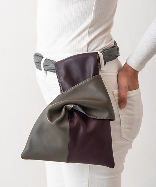 Pochette da polso Kyo, indossata come marsupio. Realizzata in vera pelle, colore grigio scuro e viola. Made in Italy